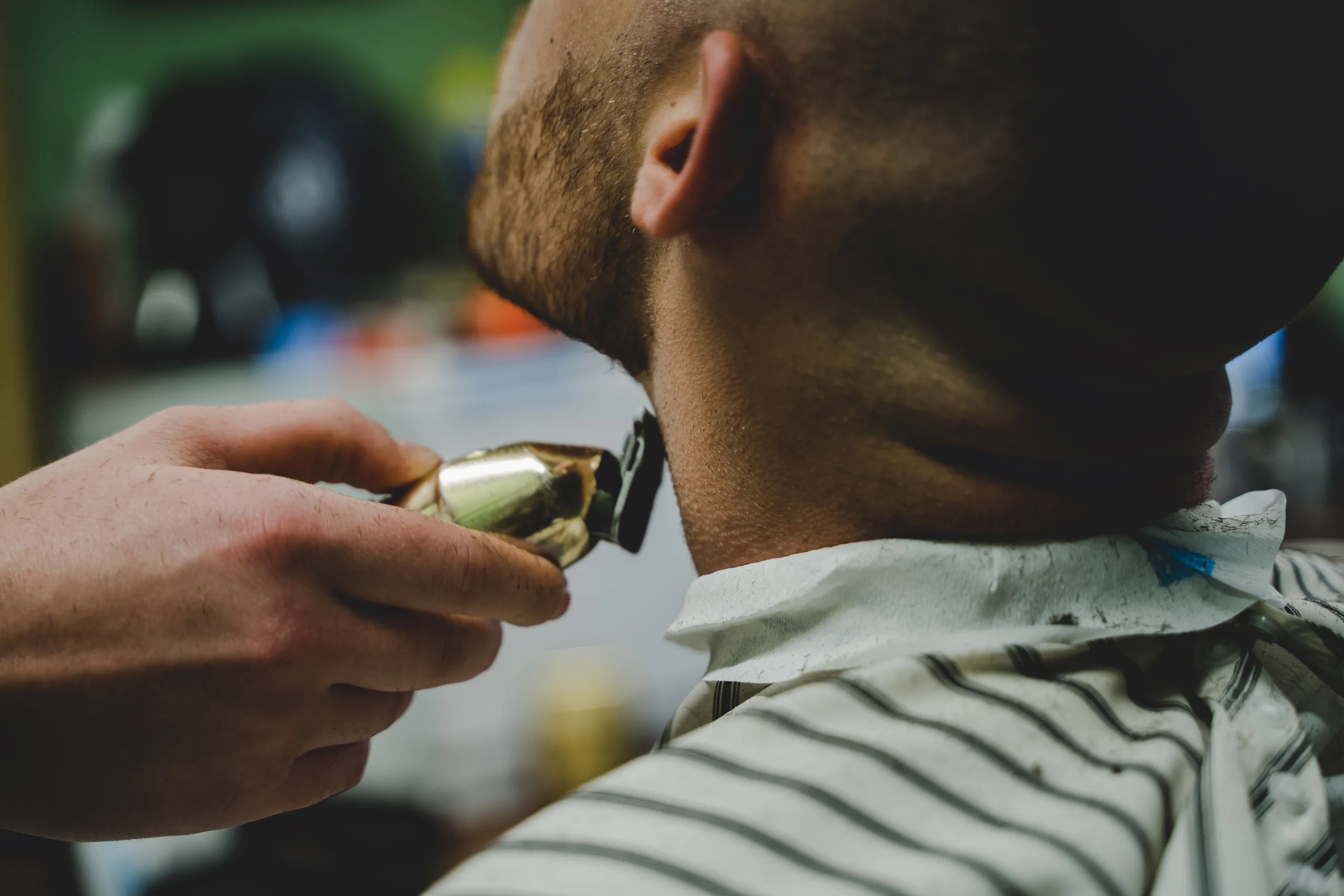 Barber trimming a client's beard with clippers