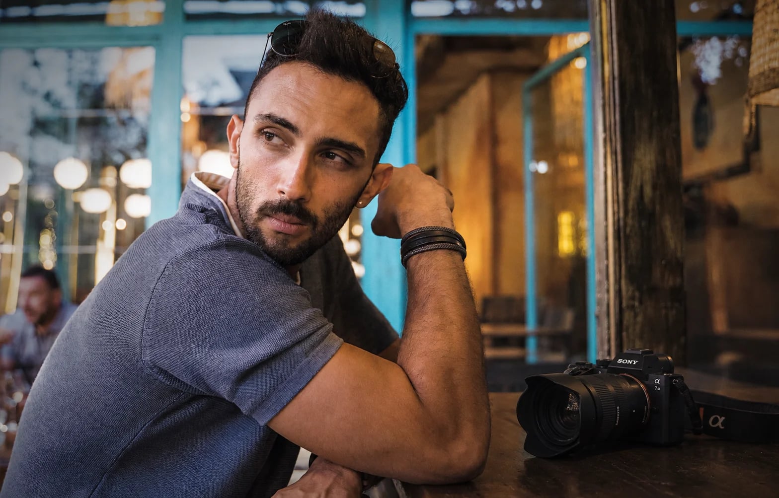 Thoughtful portrait of a man at a café table, a camera beside him