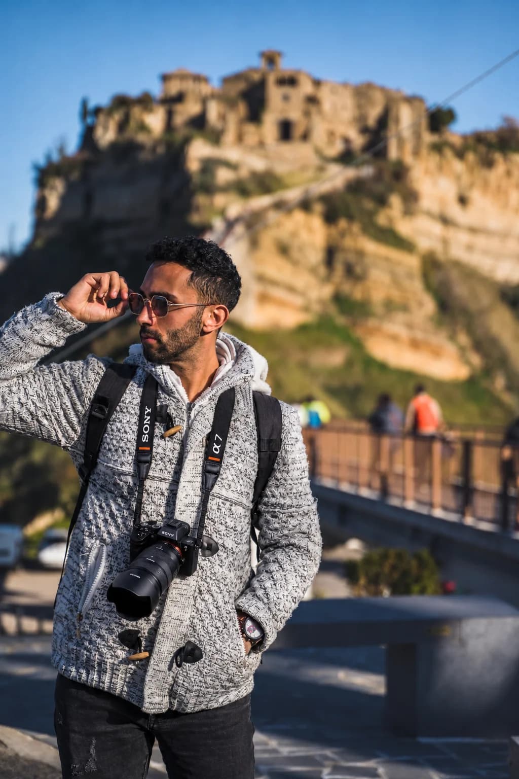 Photographer with a camera around his neck in front of a hilltop fortress